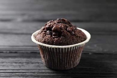 Delicious chocolate muffin on black wooden table, closeup