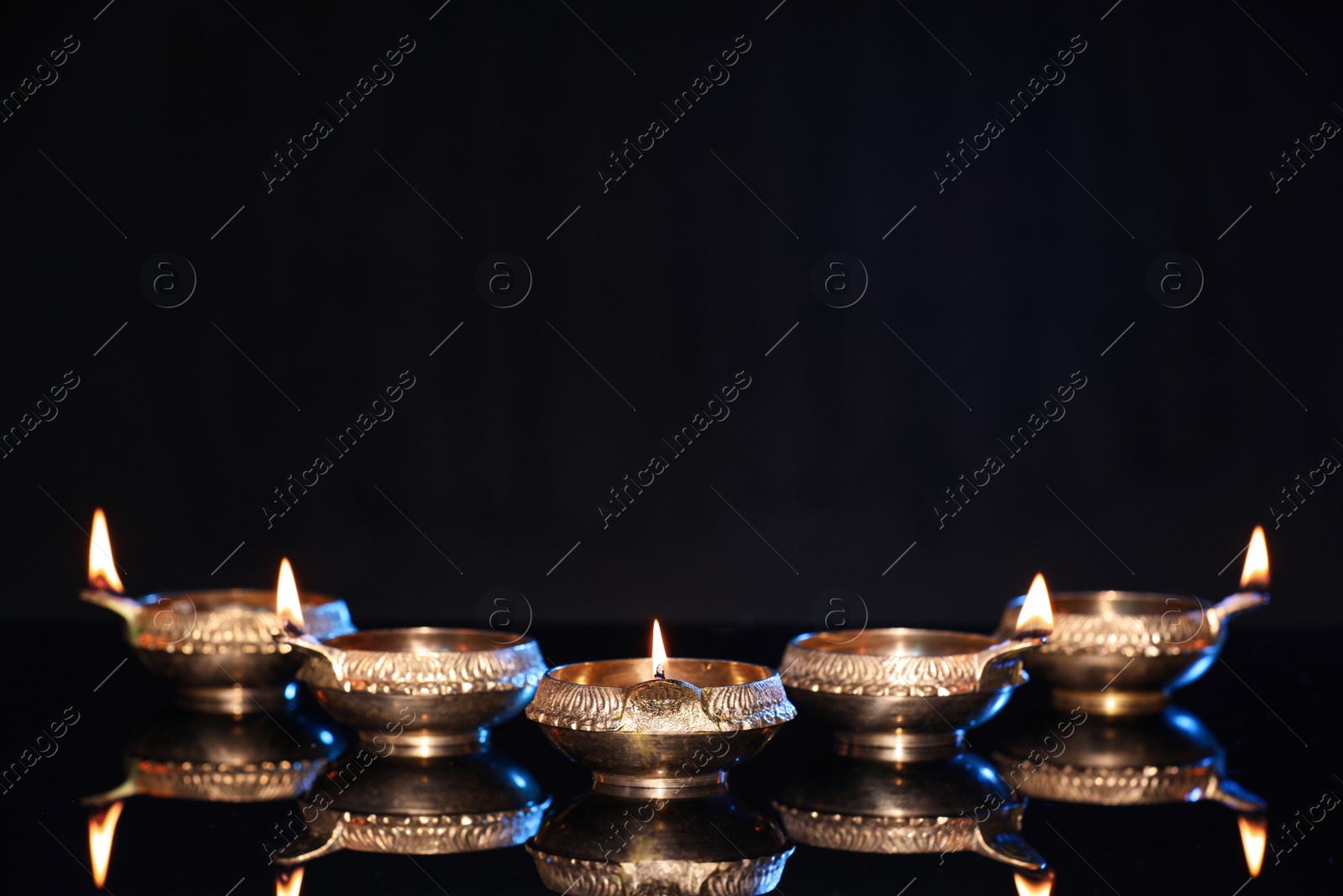 Photo of Many lit diyas on black background, space for text. Diwali lamps