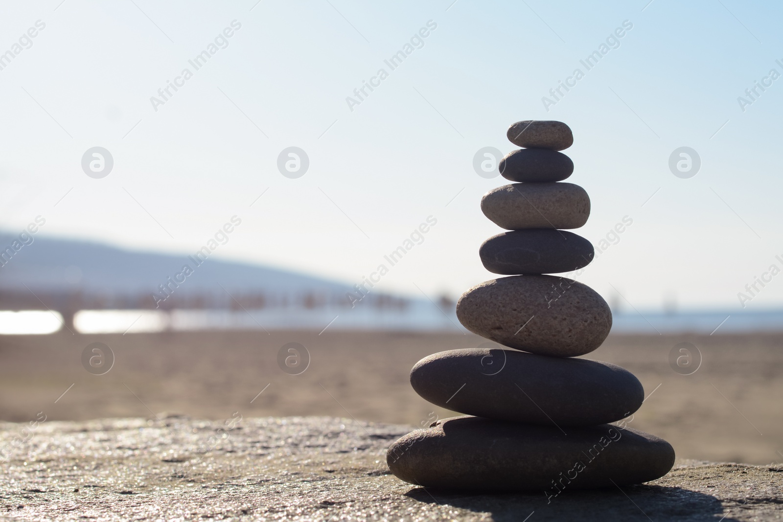 Photo of Stack of stones on parapet near sea, space for text