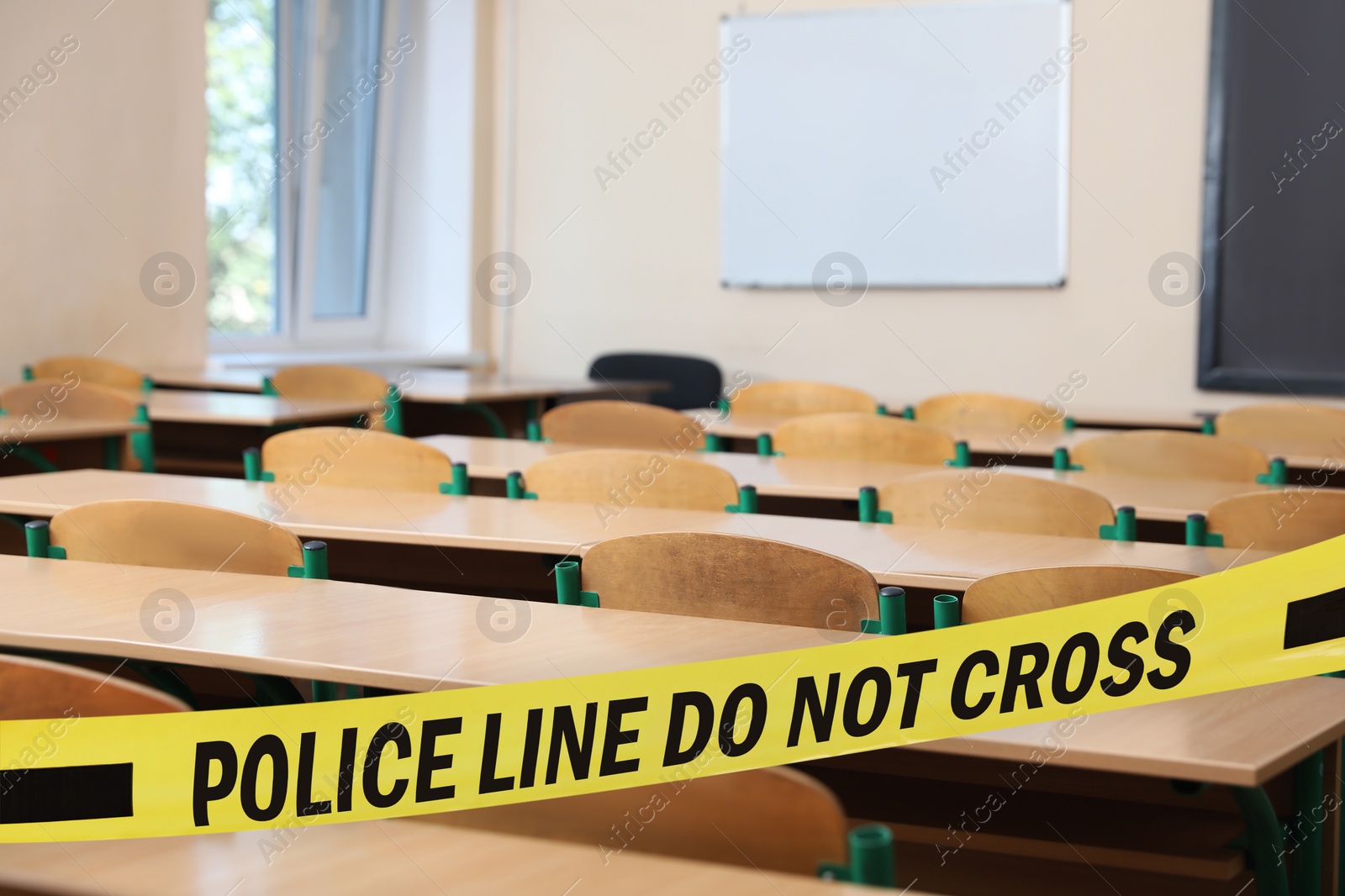 Image of Yellow crime scene tape in empty school classroom