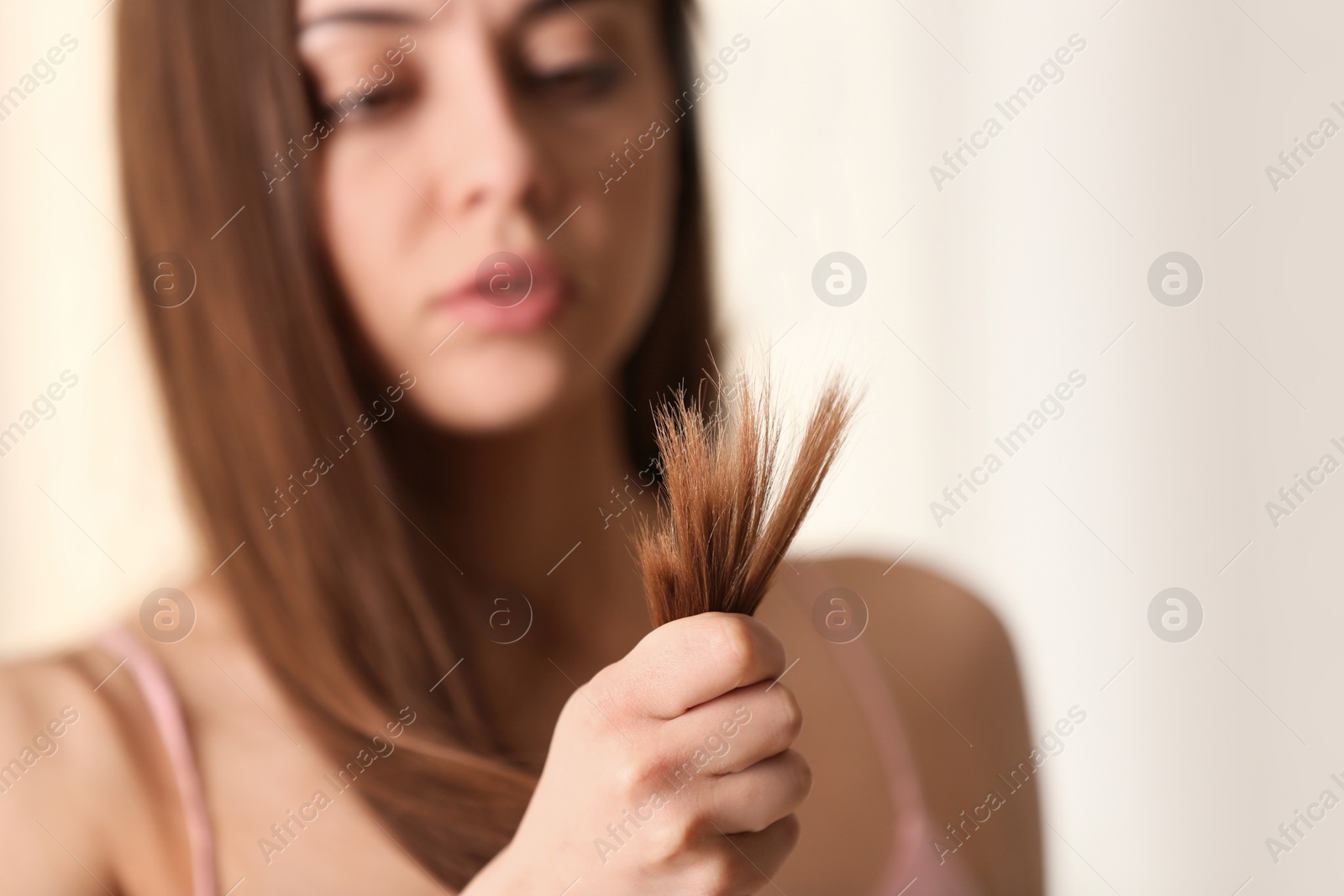 Photo of Woman with damaged hair on blurred background, selective focus. Split ends