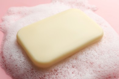 Photo of Soap with fluffy foam on pink background, closeup