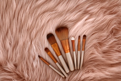Flat lay composition with makeup brushes on faux fur