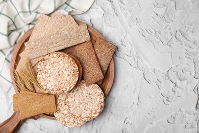 Photo of Rye crispbreads, rice cakes and rusks on white textured table, flat lay. Space for text