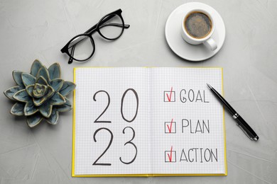 Photo of Flat lay composition of notebook with text 2023 Goal, Plan, Action on grey table. New year resolutions