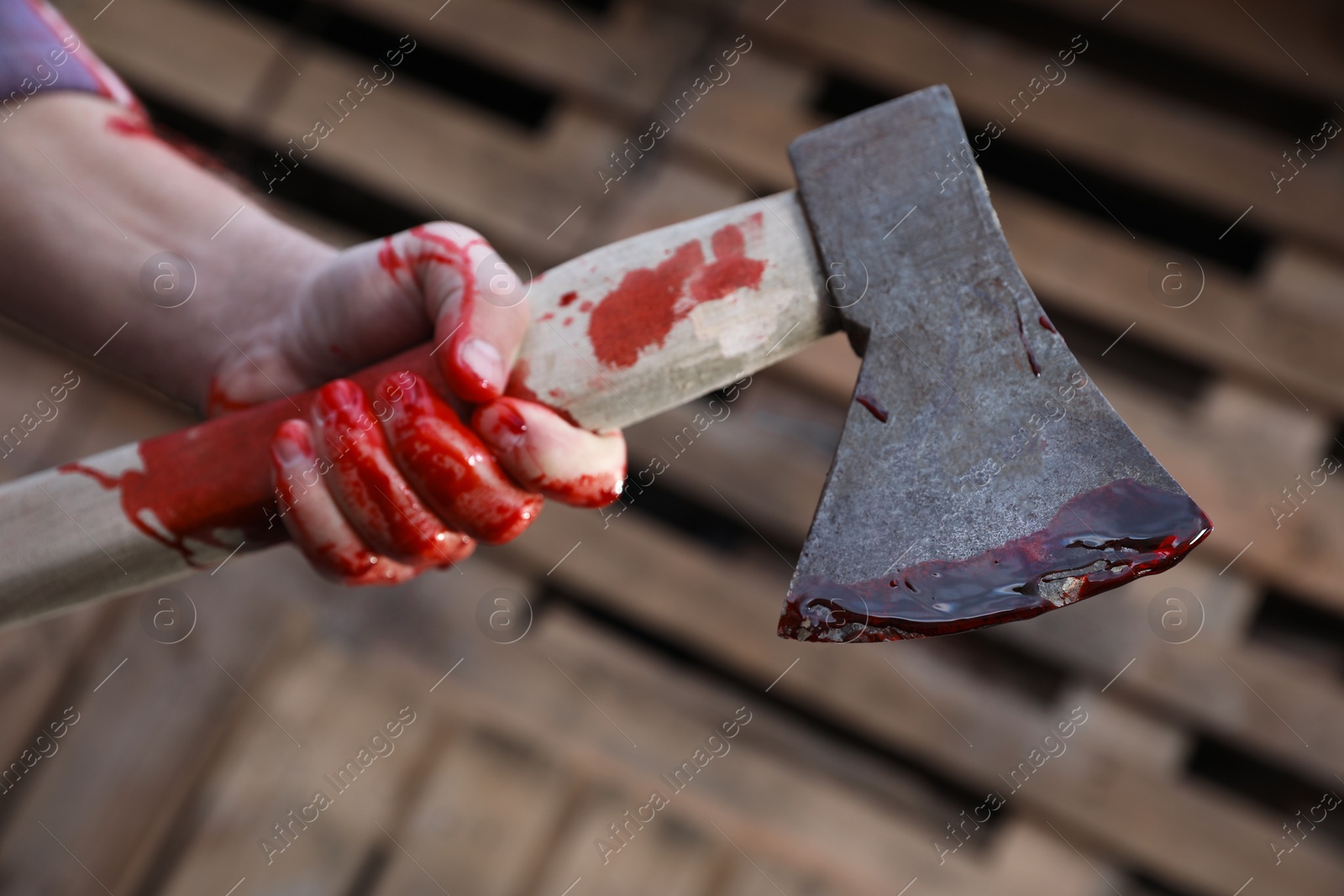 Photo of Man holding bloody axe outdoors, closeup view