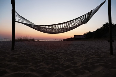 Photo of Empty hammock on beach at sunset. Time to relax