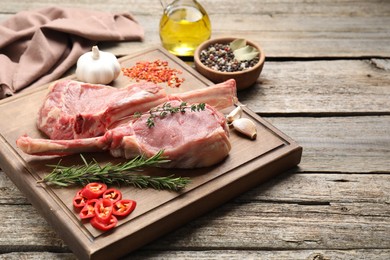 Photo of Fresh tomahawk beef cuts and spices on wooden table. Space for text