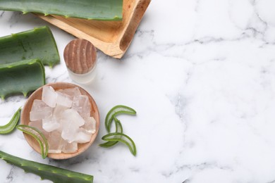 Aloe vera gel, bottle and slices of plant on white marble table, flat lay. Space for text