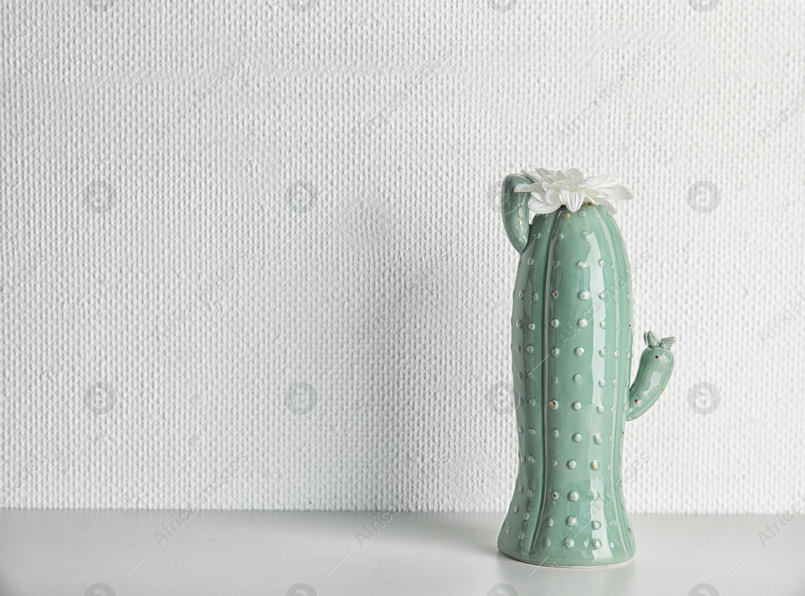 Photo of Trendy cactus shaped vase with flower on table against light wall. Creative decor