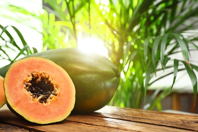 Photo of Fresh juicy ripe papayas on wooden table against blurred background, closeup view. Space for text