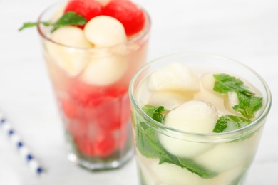 Photo of Glass with tasty melon ball drink on table, closeup