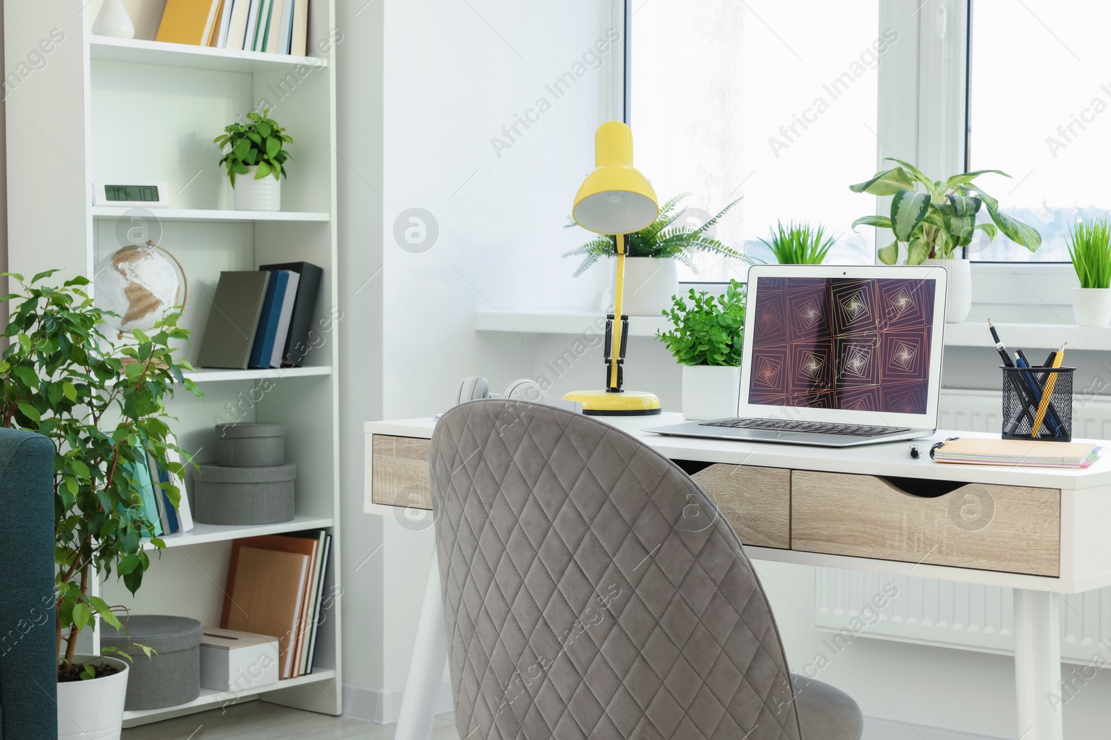 Photo of Cozy workspace with modern laptop on white wooden desk and comfortable chair at home