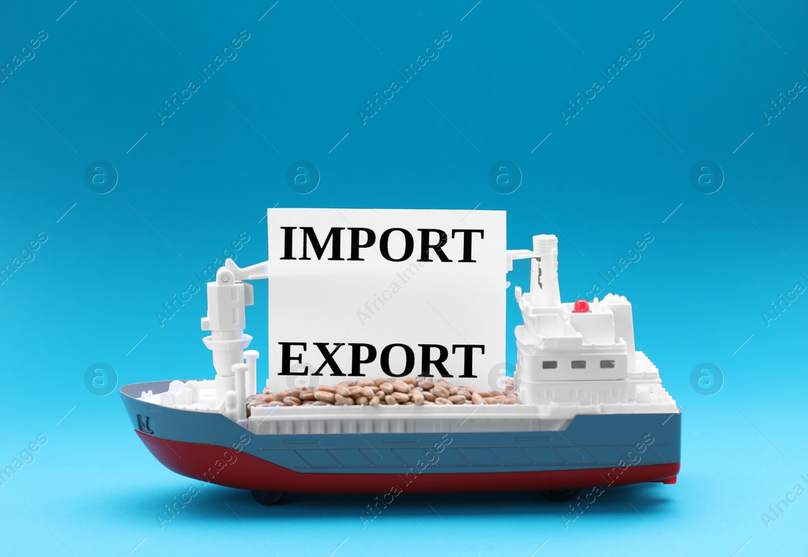 Photo of Toy cargo vessel with words Import and Export on light blue background