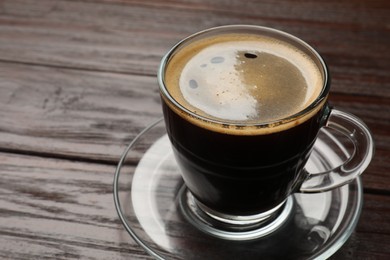 Photo of Cup of aromatic coffee on wooden table, closeup. Space for text