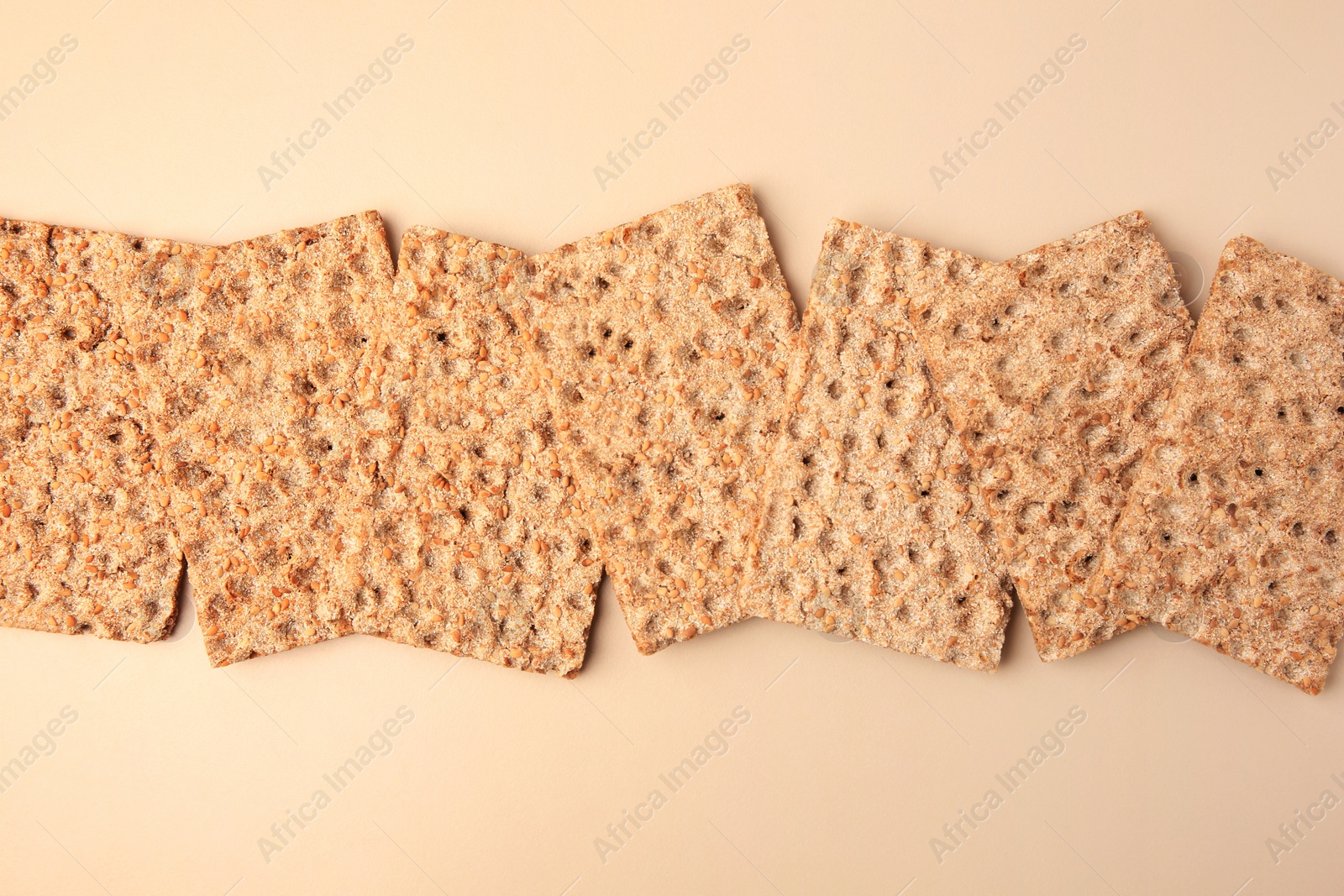 Photo of Fresh crunchy crispbreads on beige background, flat lay