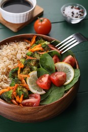 Tasty fried rice with vegetables served on green wooden table, closeup