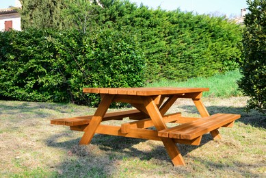 Empty wooden picnic table with benches in park on sunny day