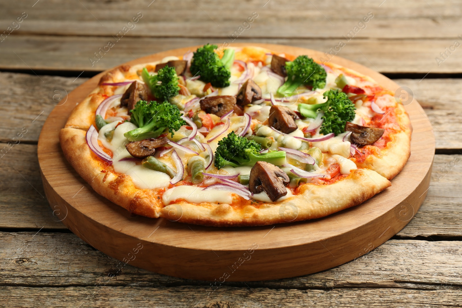 Photo of Board with delicious vegetarian pizza on wooden table, closeup