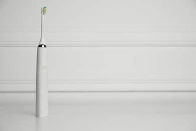 Electric toothbrush on white background, space for text