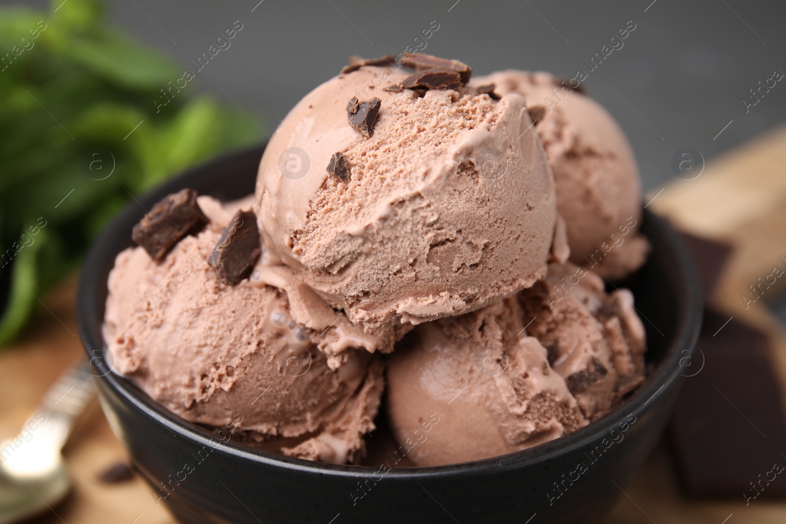 Photo of Bowl with tasty chocolate ice cream on blurred background, closeup