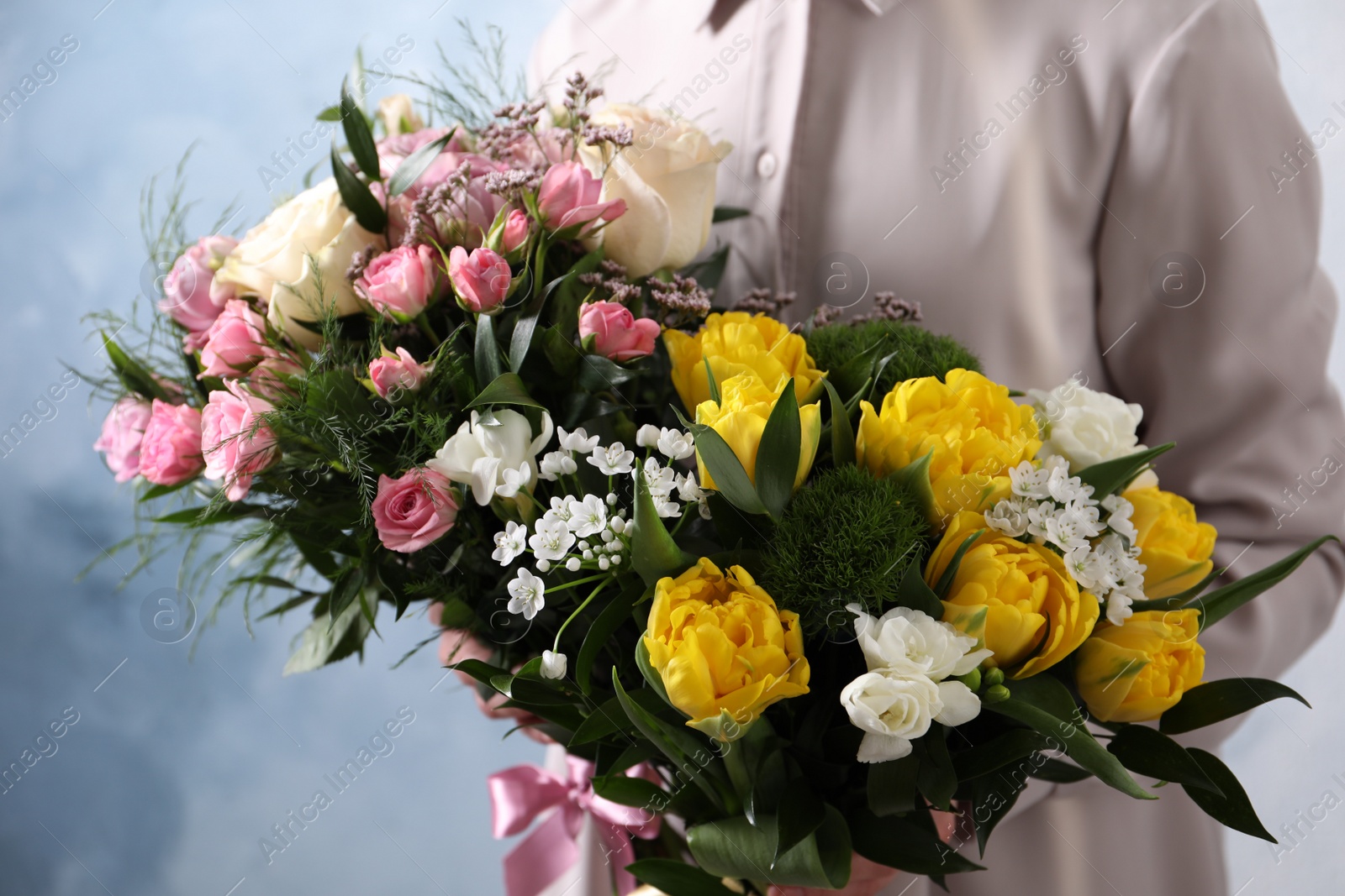 Photo of Woman with beautiful bouquets on light blue background, closeup