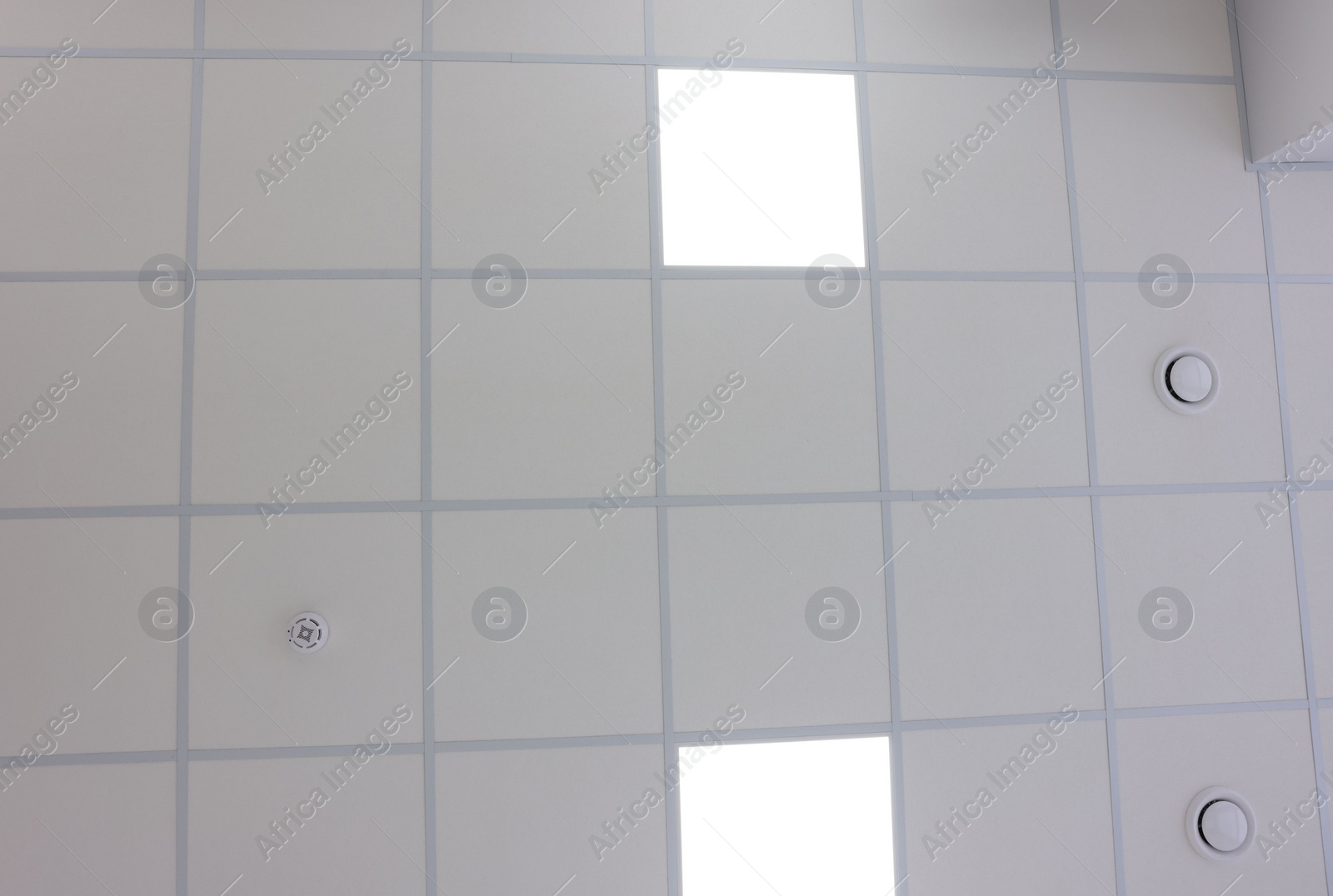 Photo of White ceiling with PVC tiles and lighting indoors, bottom view