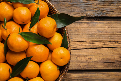 Fresh ripe tangerines with leaves on wooden table, top view. Citrus fruit