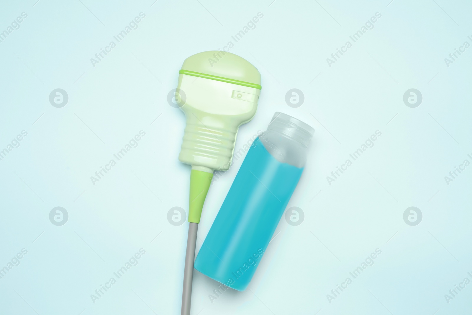 Photo of Ultrasonic transducer and ultrasound transmission gel on light background, flat lay