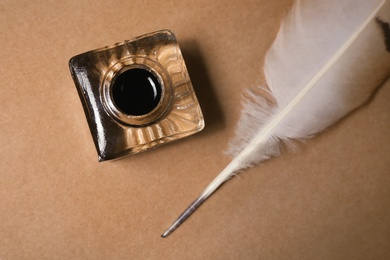 Feather pen and inkwell on old parchment, top view