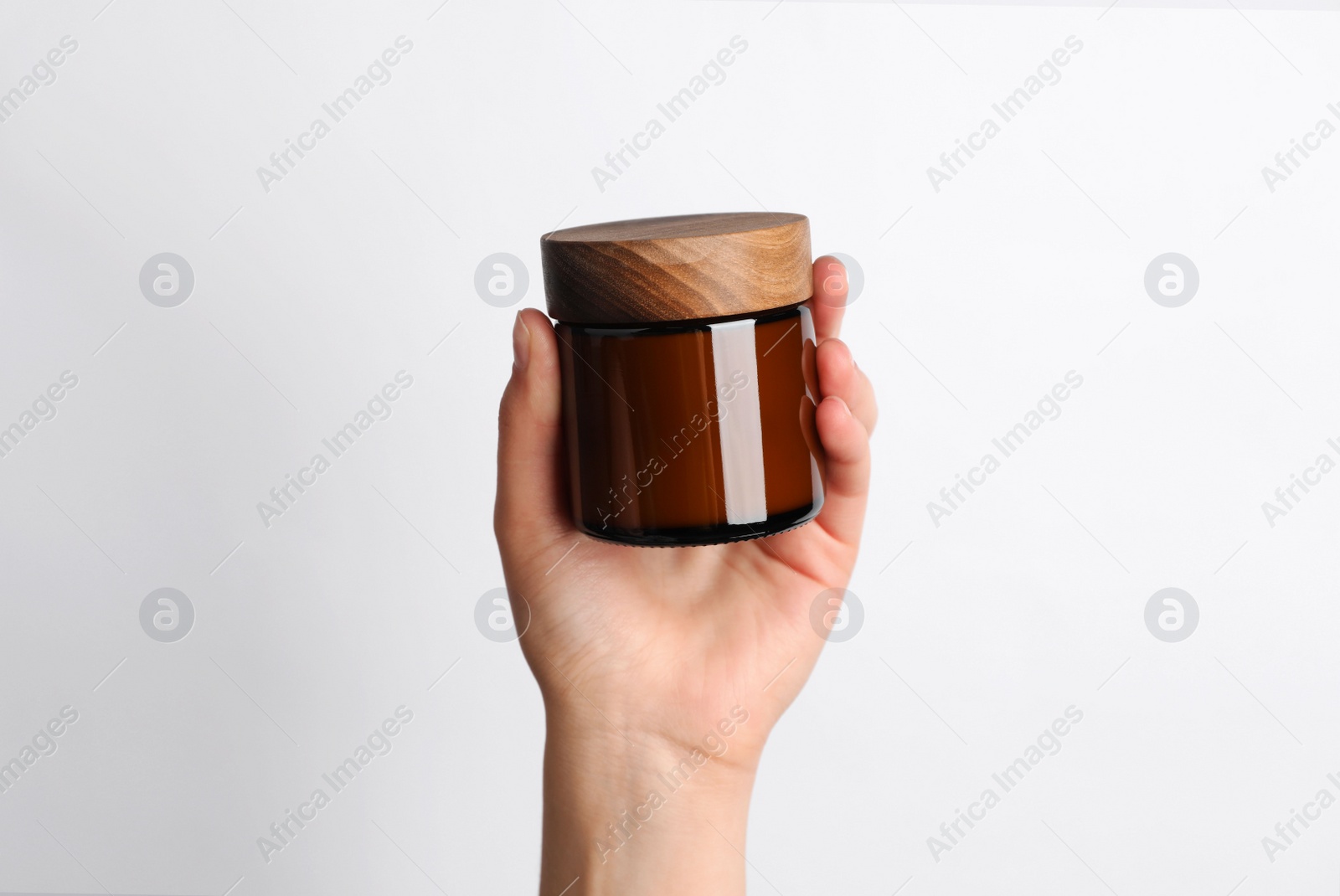 Photo of Woman holding jar of face cream on white background, closeup