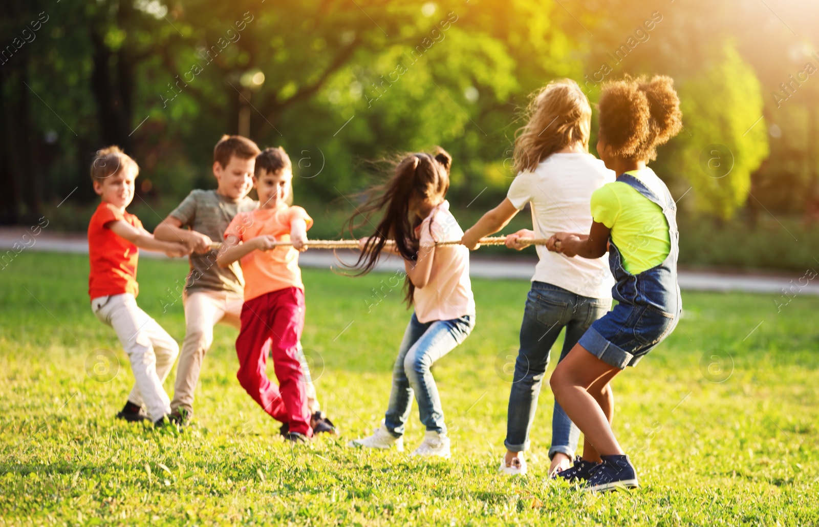 Image of School holidays. Group of happy children playing with rope outdoors 