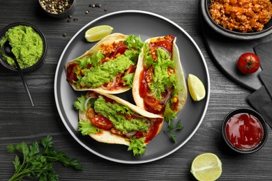 Photo of Delicious tacos with guacamole, meat and vegetables on wooden table, flat lay