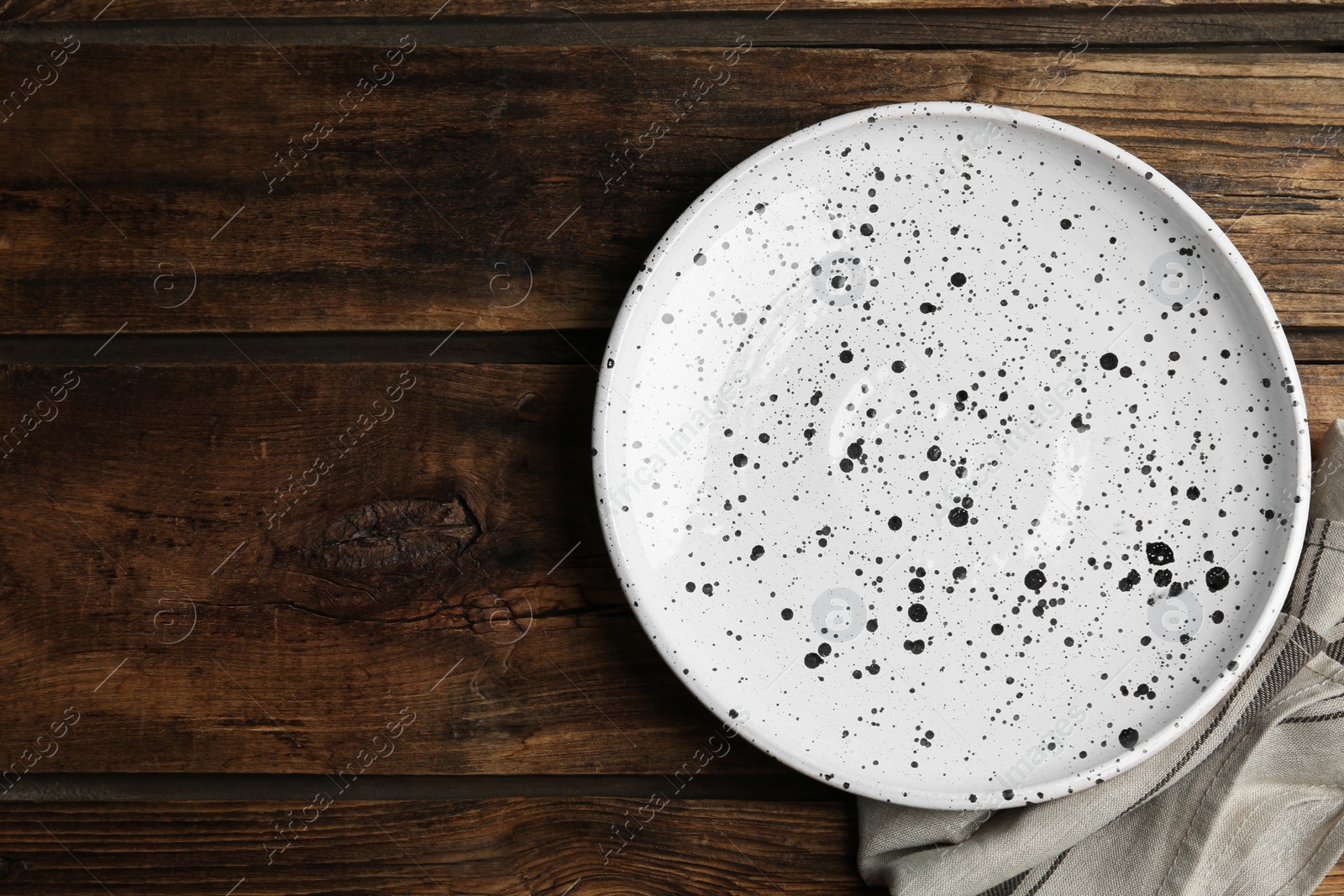 Photo of Empty patterned plate and napkin on wooden table, flat lay. Space for text