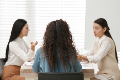 African American woman and her coworkers in office, back view. Racism at work