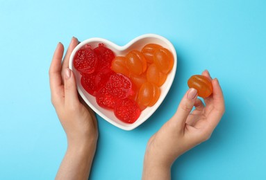 Photo of Woman with delicious gummy candies on light blue background, top view