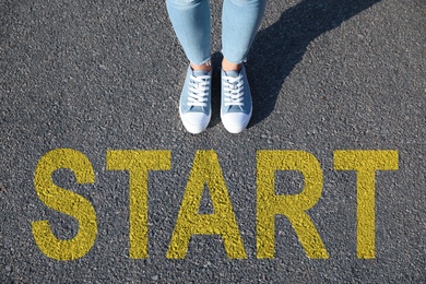 Word Start on asphalt in front of woman, above view