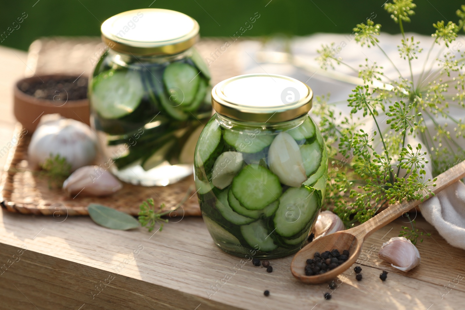 Photo of Jars of delicious pickled cucumbers and ingredients on wooden table