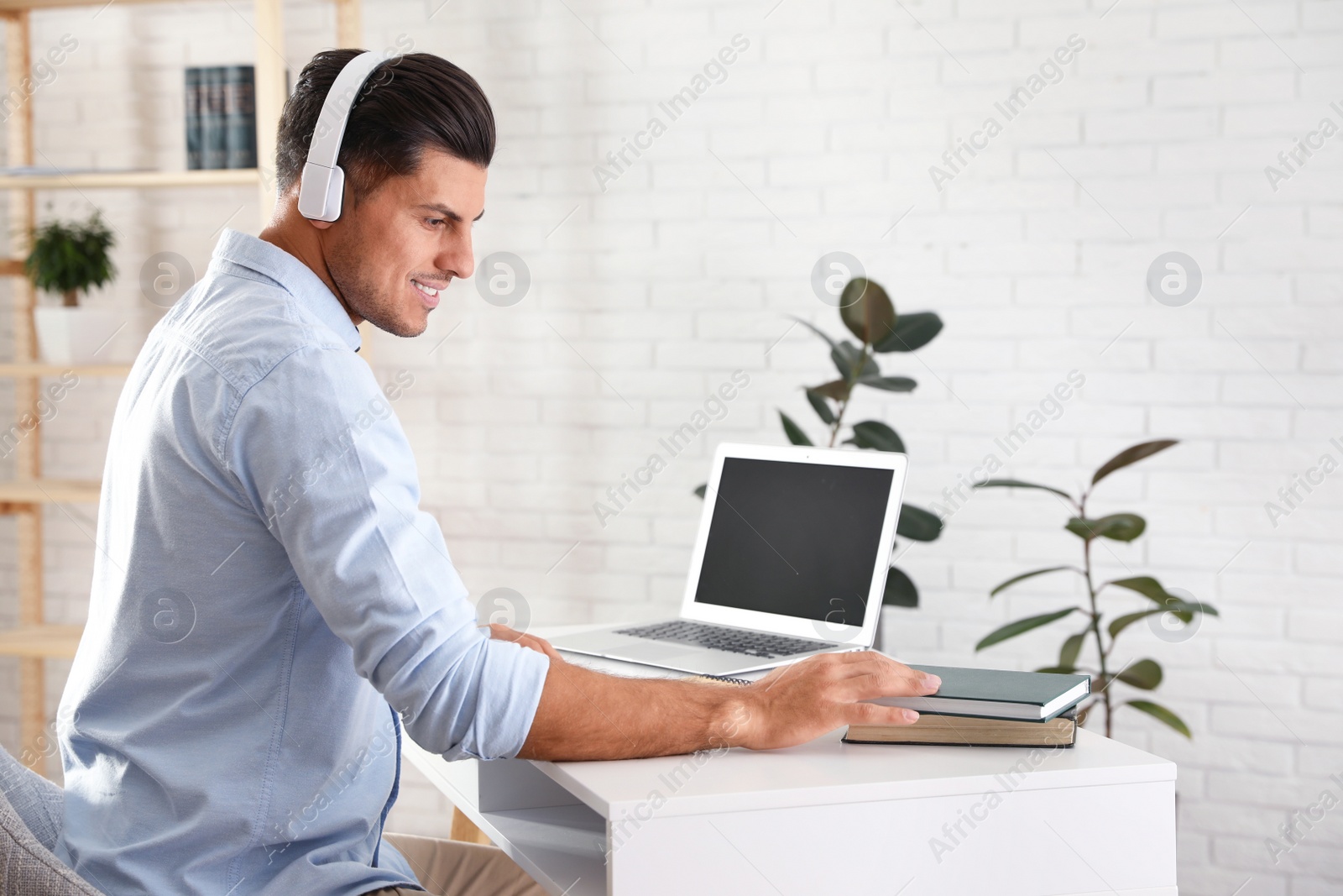 Photo of Man listening to audiobook at table with laptop