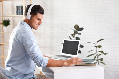 Man listening to audiobook at table with laptop