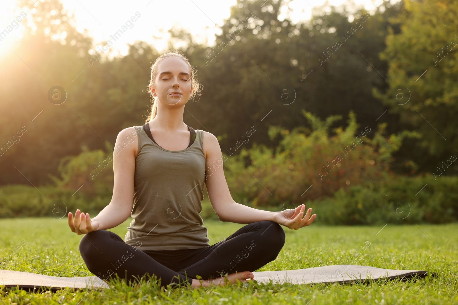 Photo of Beautiful woman practicing yoga outdoors on sunny day. Lotus pose