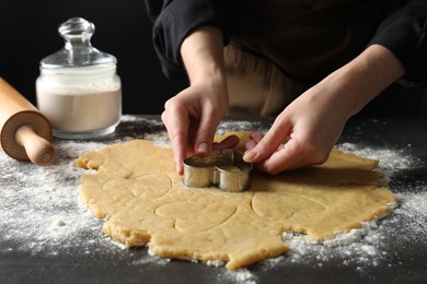 Shortcrust pastry. Woman making cookies with cutter at grey table, closeup