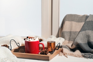 Photo of Tray with cup of cocoa on windowsill, space for text. Winter drink