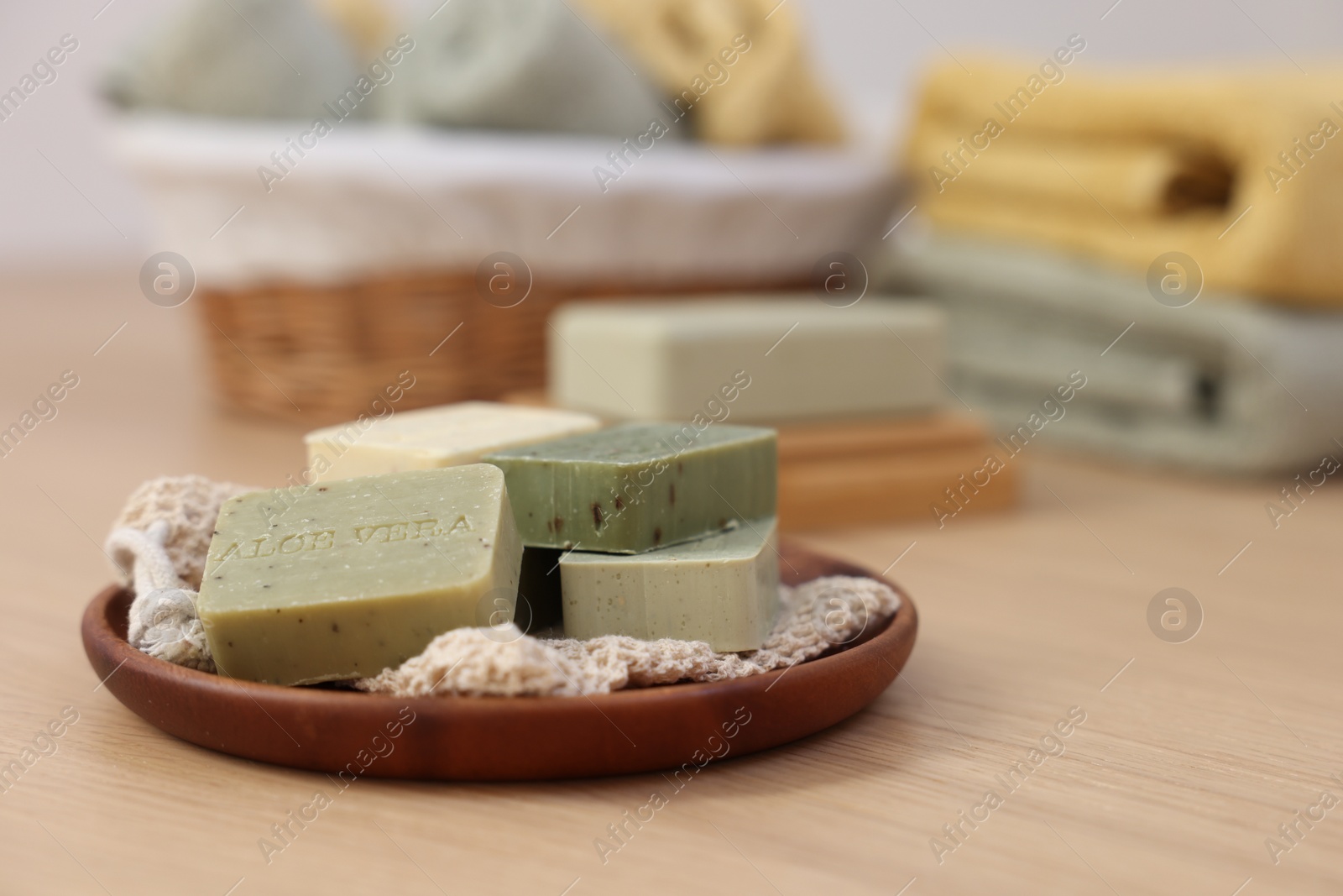 Photo of Tray with soap bars on light wooden table, space for text. Spa therapy