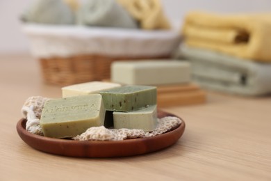 Tray with soap bars on light wooden table, space for text. Spa therapy