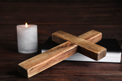 Cross, Bible and burning candle on wooden background, closeup. Christian religion