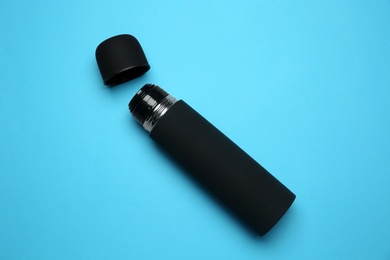 Photo of Black thermos on light blue background, top view
