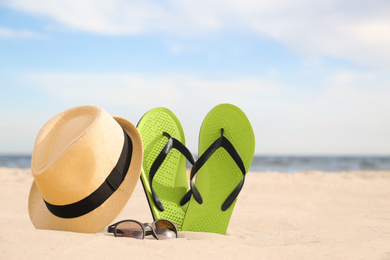 Different stylish beach objects on sand near sea