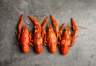 Delicious boiled crayfishes on grey table, flat lay
