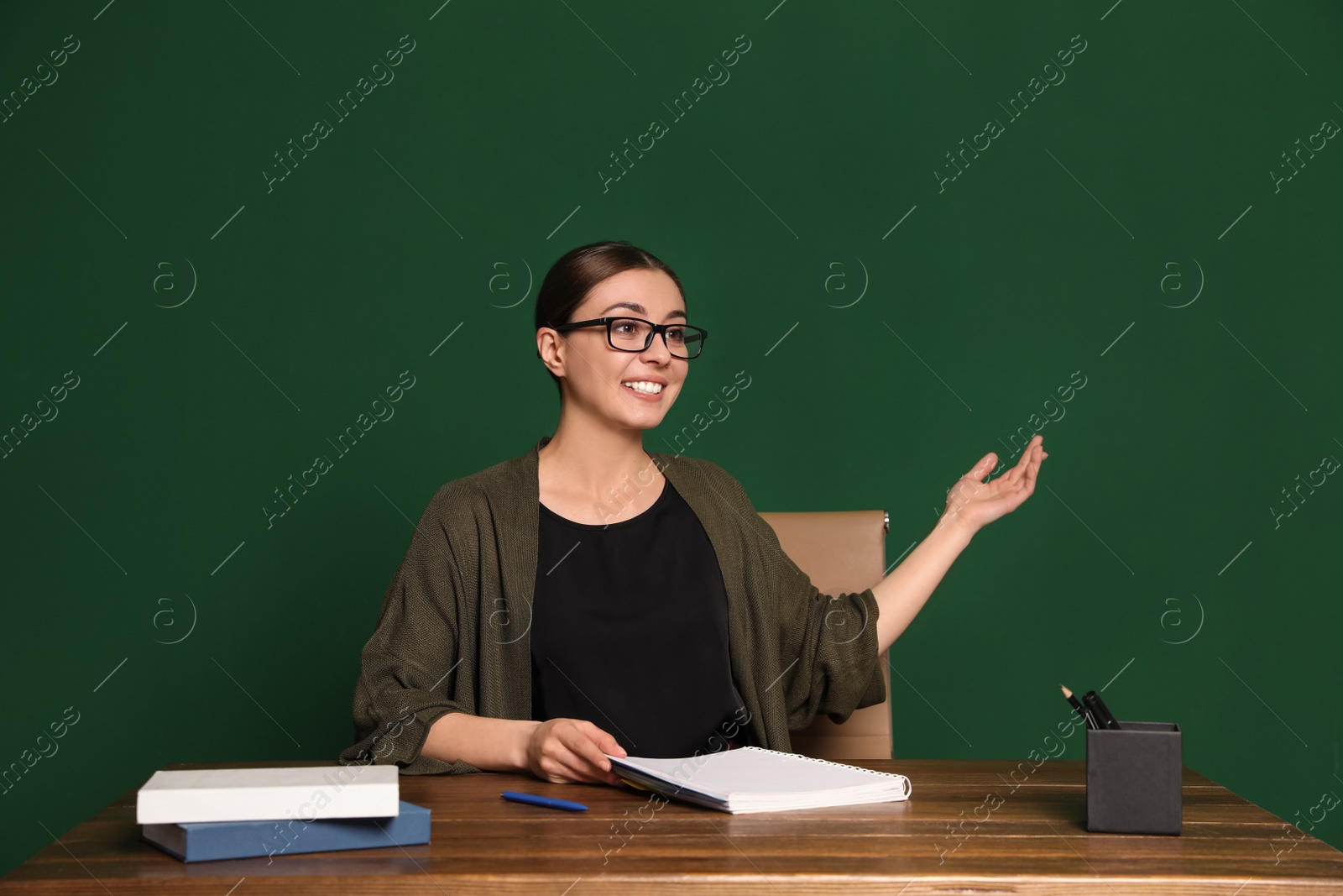 Photo of Portrait of young teacher at table against green background